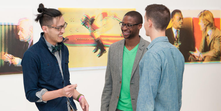 Three young adults talking in front of artwork.
