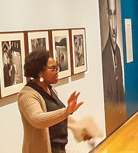 A Black woman talking to a group of students