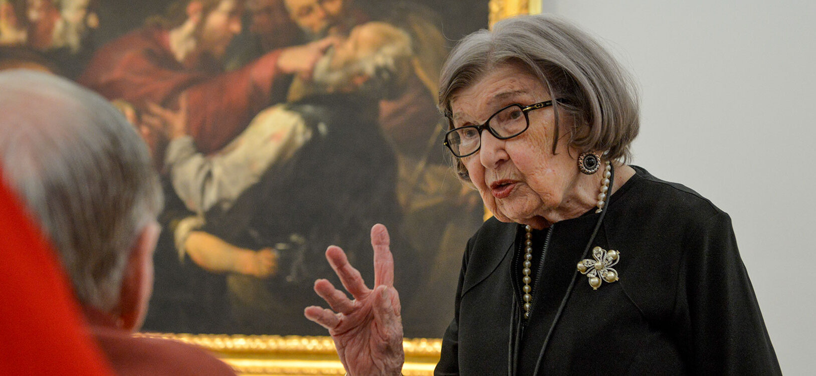 An art docent givinga tour to an elderly museum visitor