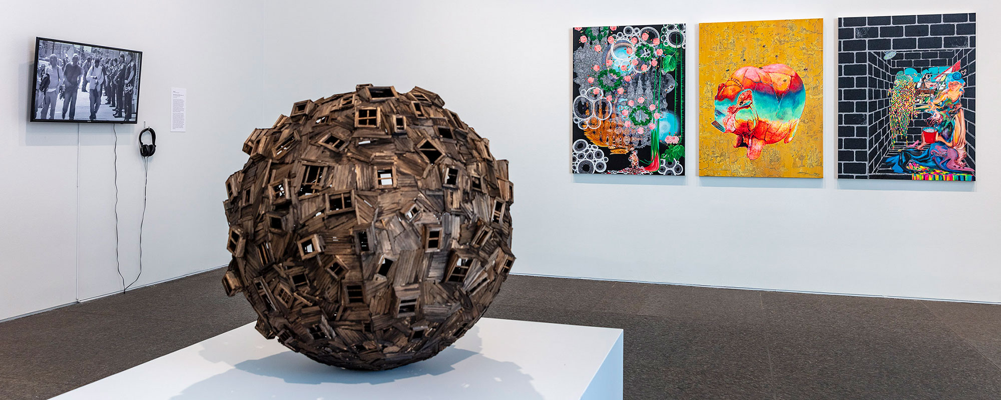 A view of an art gallery with a wooden sphere in the foreground