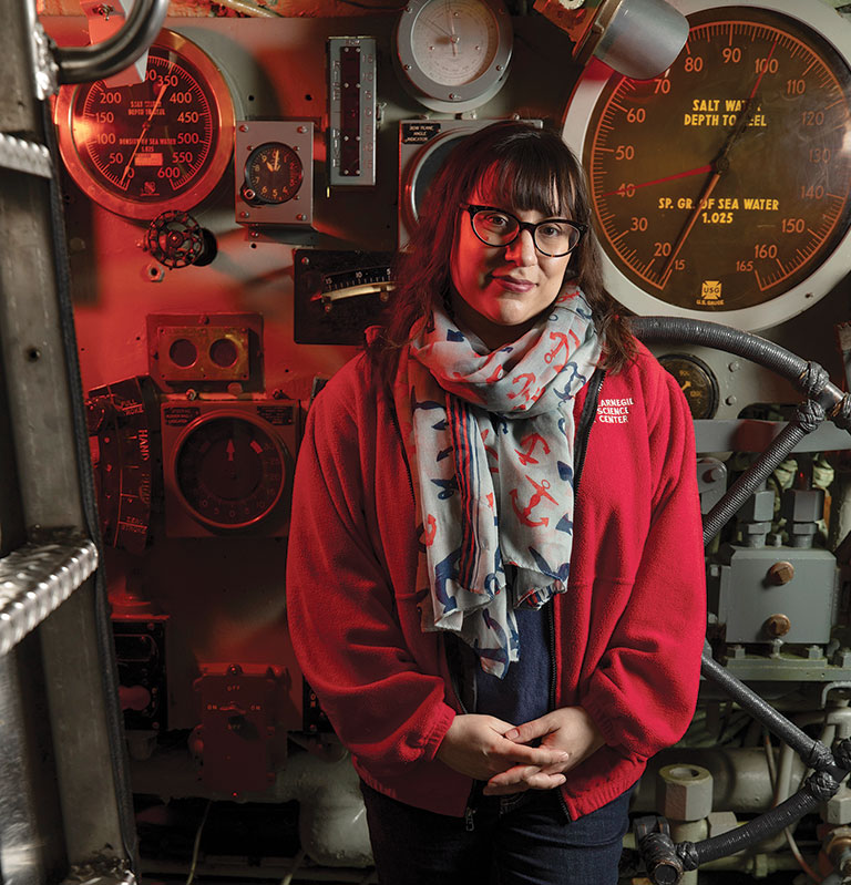 A portrait of a woman standing inside of a submarine