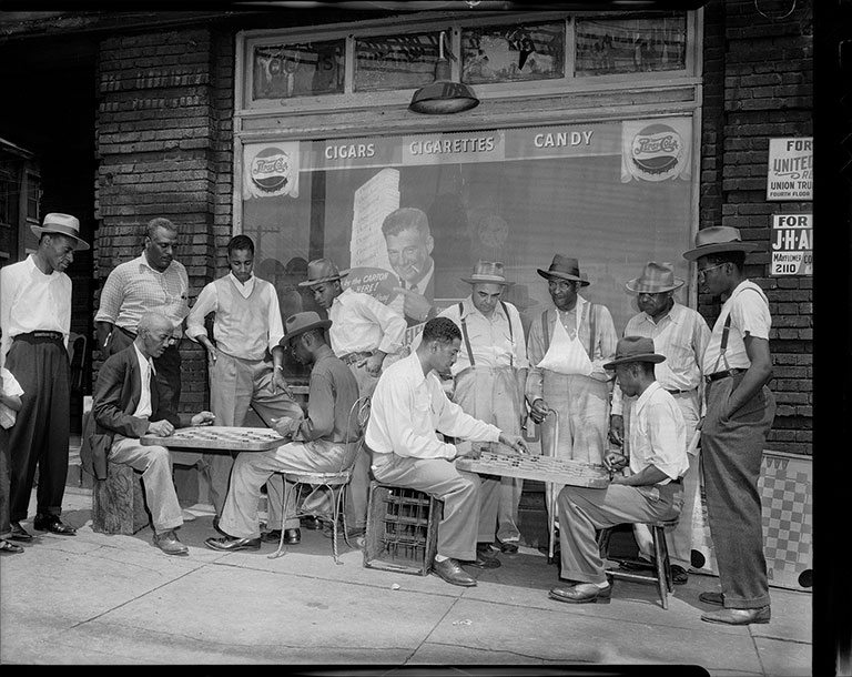 A group of men playing checkers in front of a store