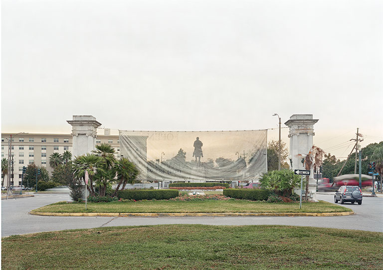 A panoramic view of a statue of a man behind a transparent screen material