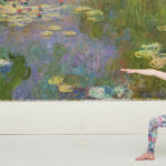 A woman holding a yoga stance in front of artwork in a gallery
