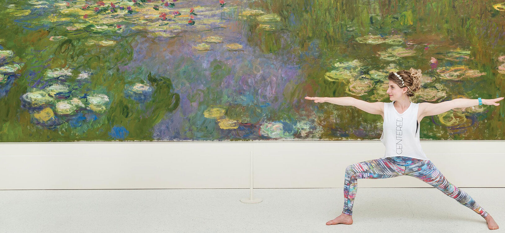 A woman holding a yoga stance in front of artwork in a gallery