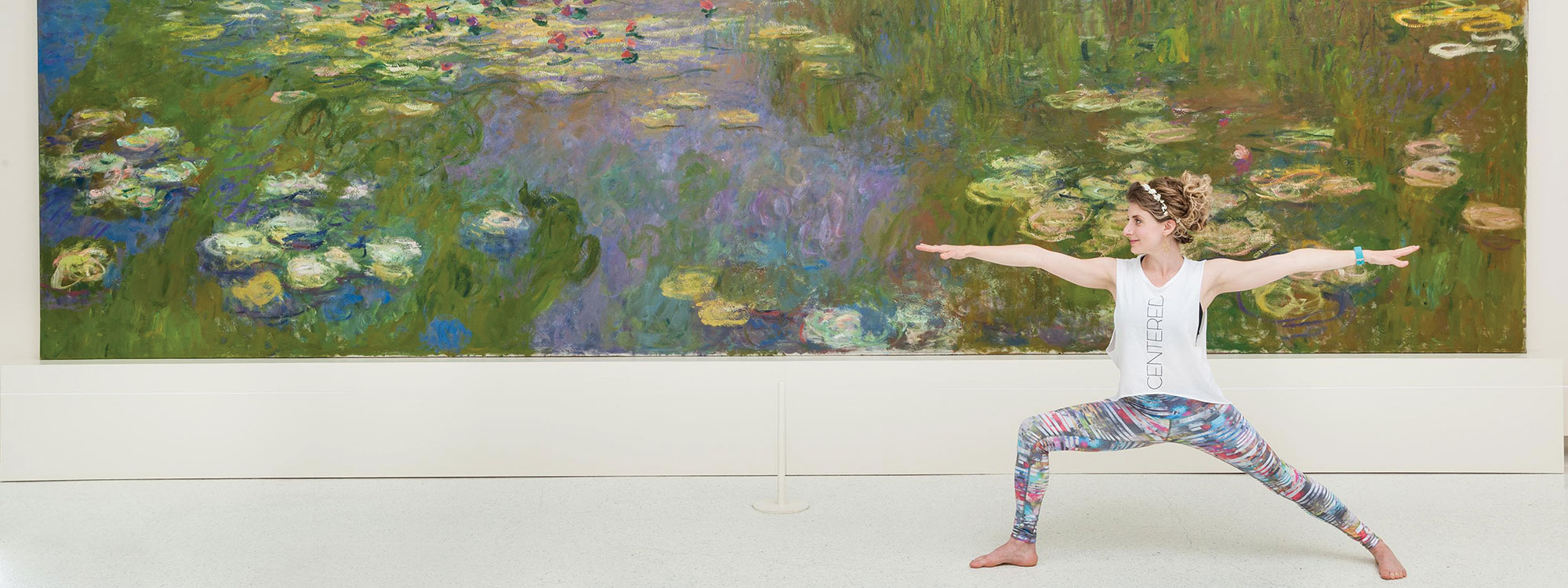 A woman holding a yoga stance in front of artwork in a gallery