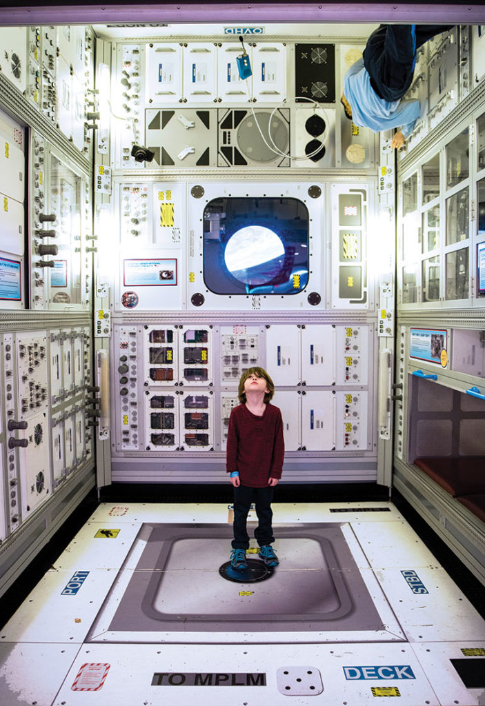 A young boy standing in Carneige Science Center's Space Place, looking up towards the ceiling.
