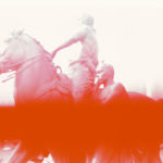 A photo of a sculture of a man on a horse with another man walking beside him. The photo has a large blurred red line across it.