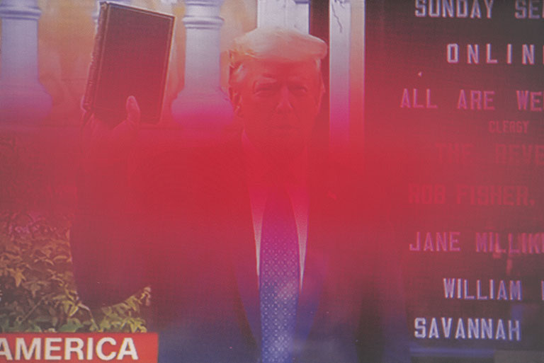 A photo of Donald Trump holding up a bible with a red blurred area crossing over the photo