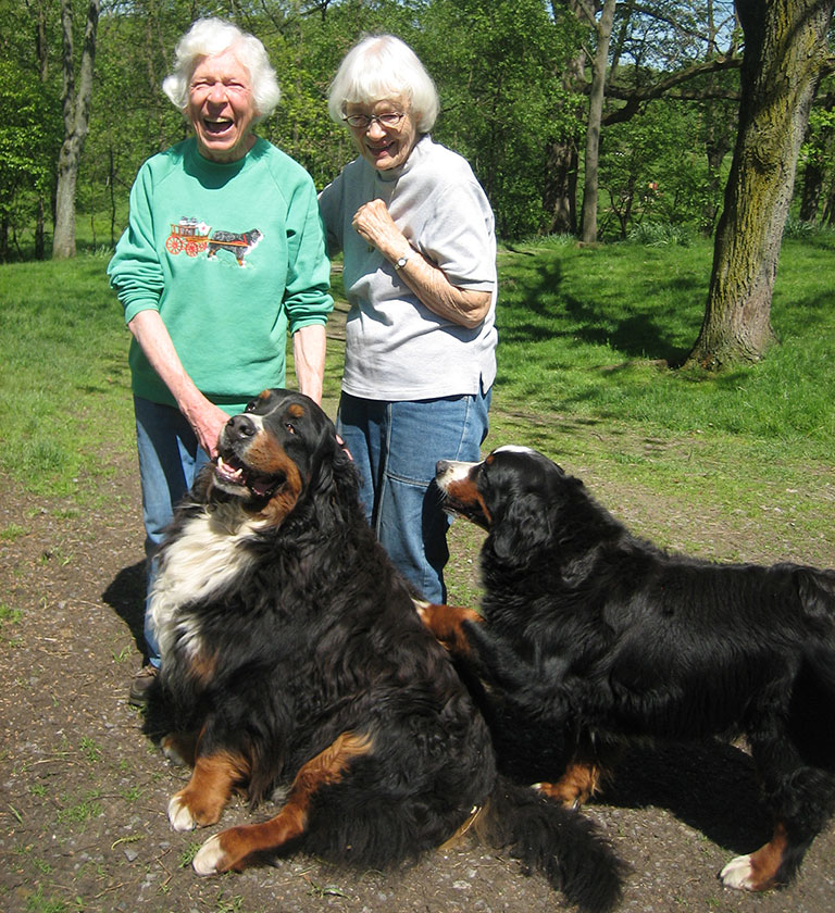 2 women standing with 2 large dogs