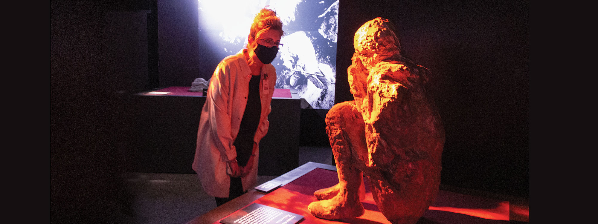 A women in the Pompeii exhibit looking at a human cast