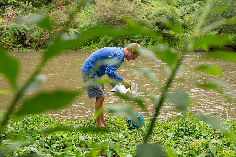 A man testing water from a river