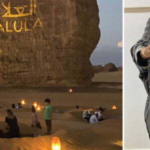 An outdoor scene from an exhibition with Alula projected on to a large rock formation and a young girl holding her artwork