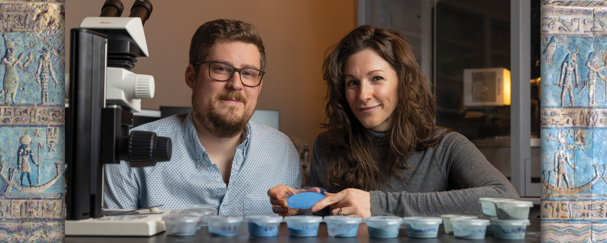 Two scientists posing with a blue powder in a petri dish
