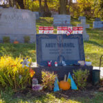 A cemetery with headstones containing names of Andy Warhol and another with the name Warhola.
