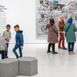 An art museum educator leading a tour of immigrant families through the museum.