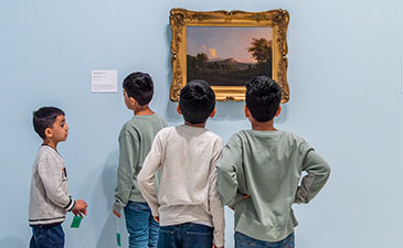 A group of young boys looking at a painting.