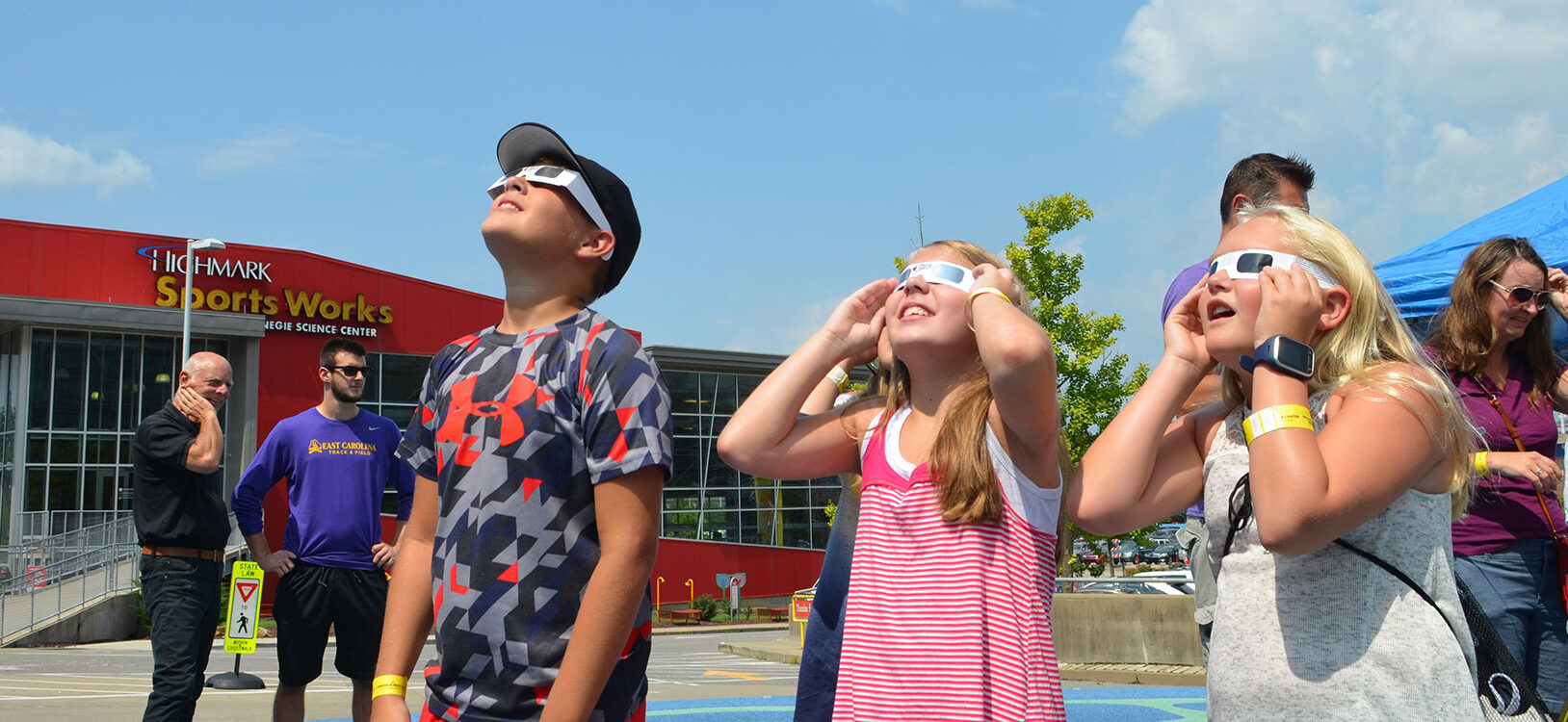 A group of children staring at the solar eclipse wearing protective glasses.