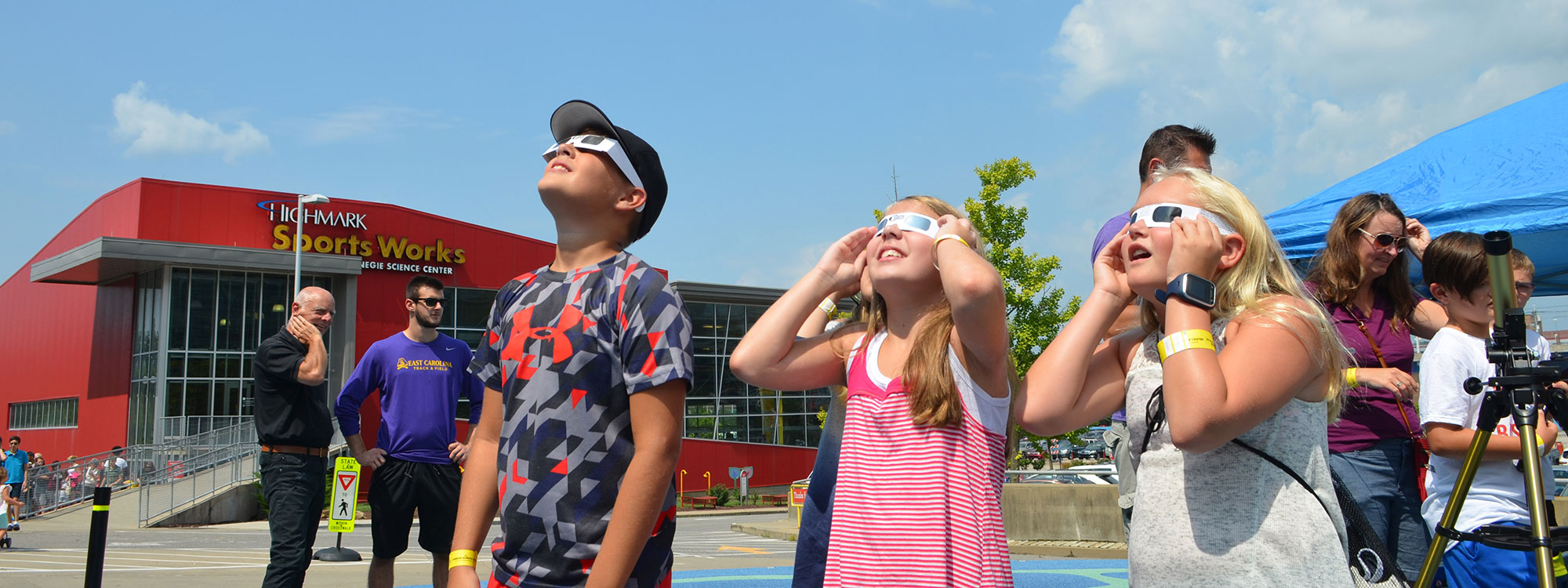 A group of children staring at the solar eclipse wearing protective glasses.