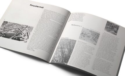 An open magazine features two pages with black-and-white photographs and text. The left page shows snow-covered branches, while the right has varied nature images. The tone is reflective.