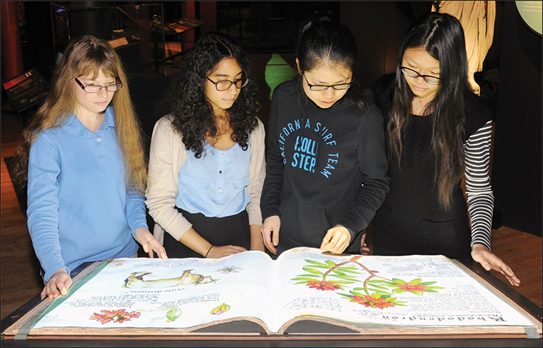 a group of young girls looking at a large book