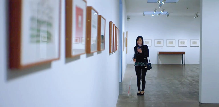 A blind woman in an art museum using an audio guide