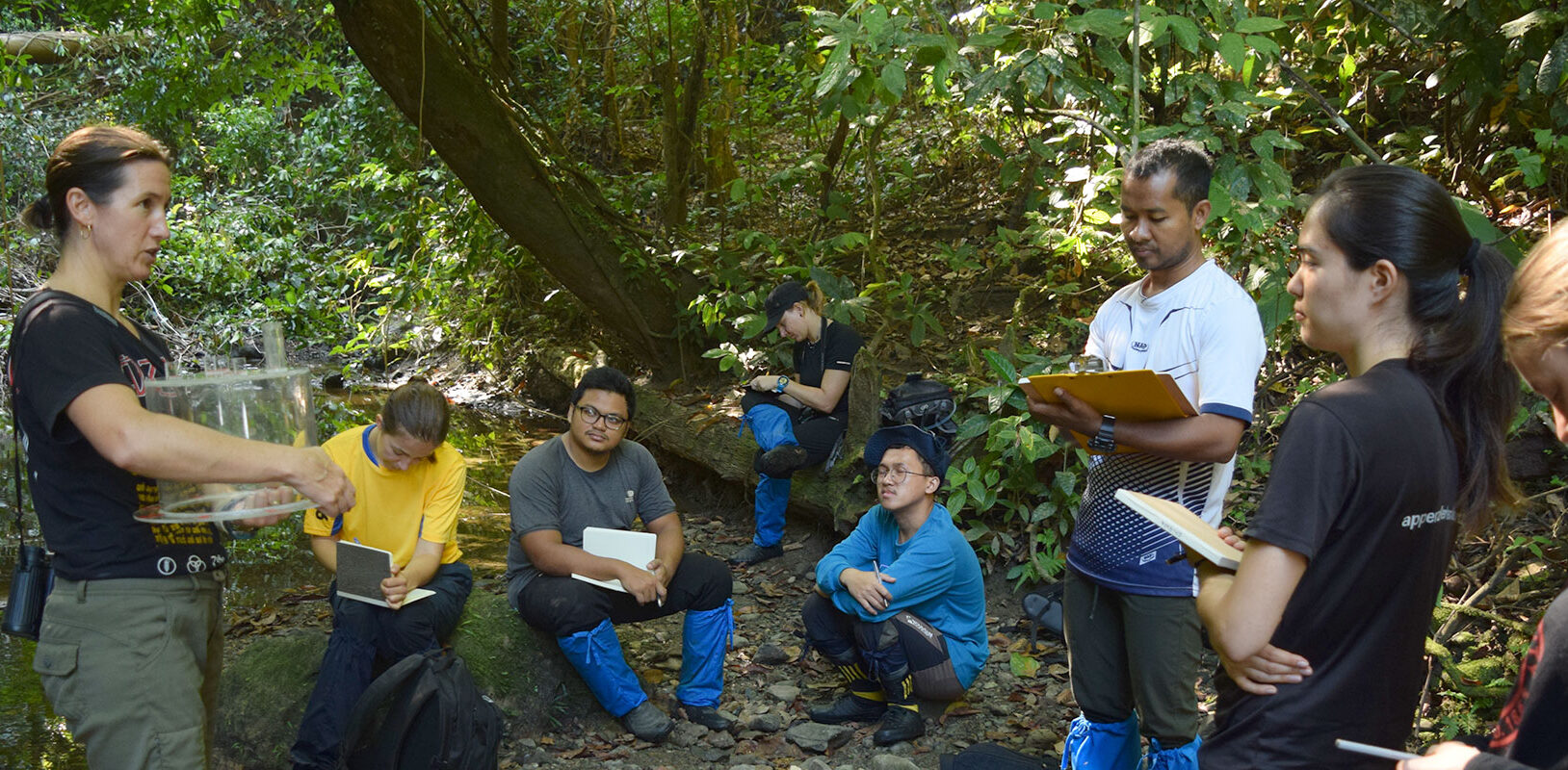 a woman instructs a group of graduate students on in the rainforests of Malaysian Borneo.