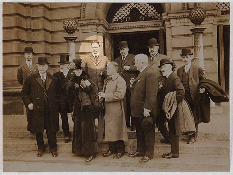 An old photo of a group of people on the steps of the museum.