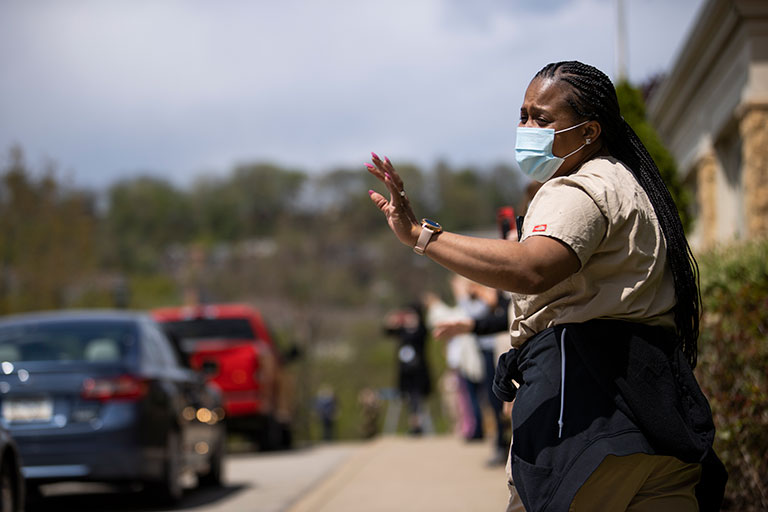 A front line worker waving at passing cars.