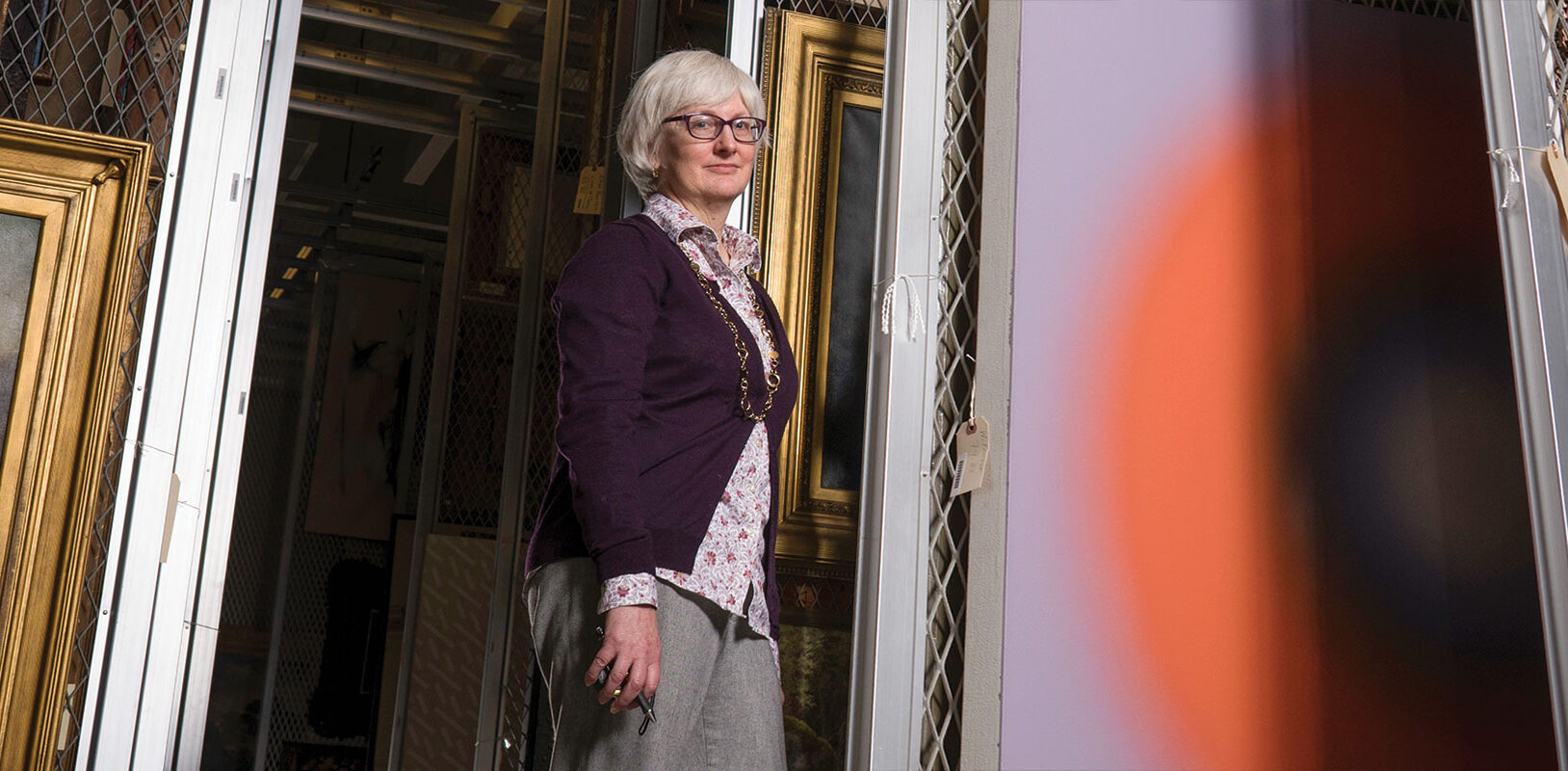 Portrait ohoto fo Elizabeth Tufts Brown standing in art storage area.