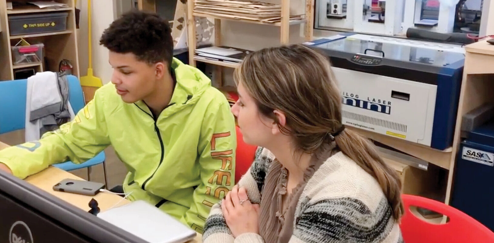 A teen and a mentor working on a project.