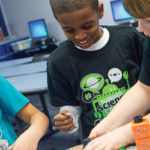 A group of children laughing and working on a science project