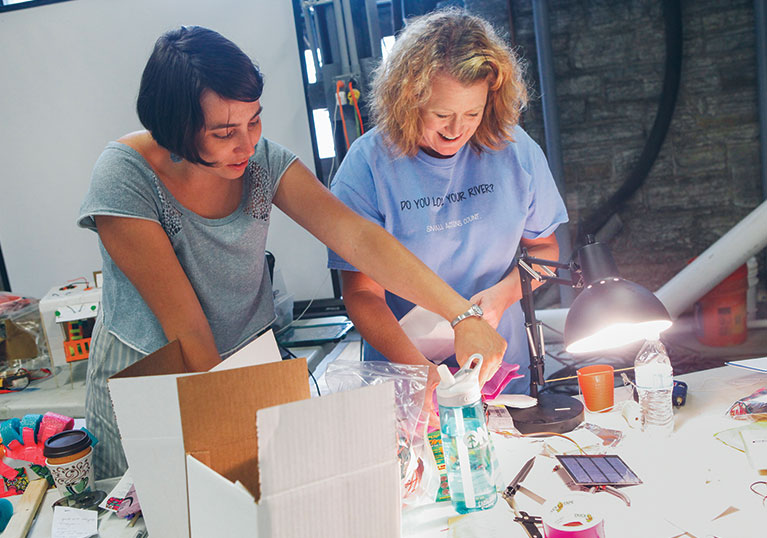 Two woman working at a table on a project