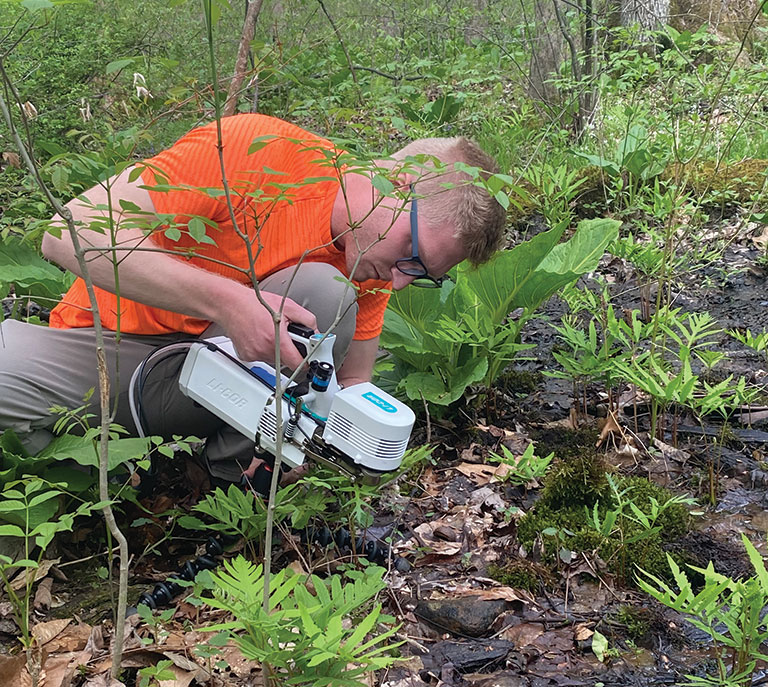A scientist studying plants near a stream