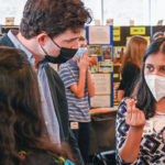 A young firl at a science fair talking to an adult