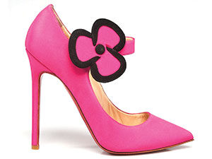 A pink, high-heeled shoe with a large flower shaped buckle