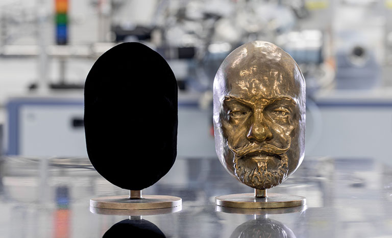 A photo of the 2 busts of a head of a man. One is painted black.