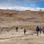 A group walking away from the camera in a large desolate area.
