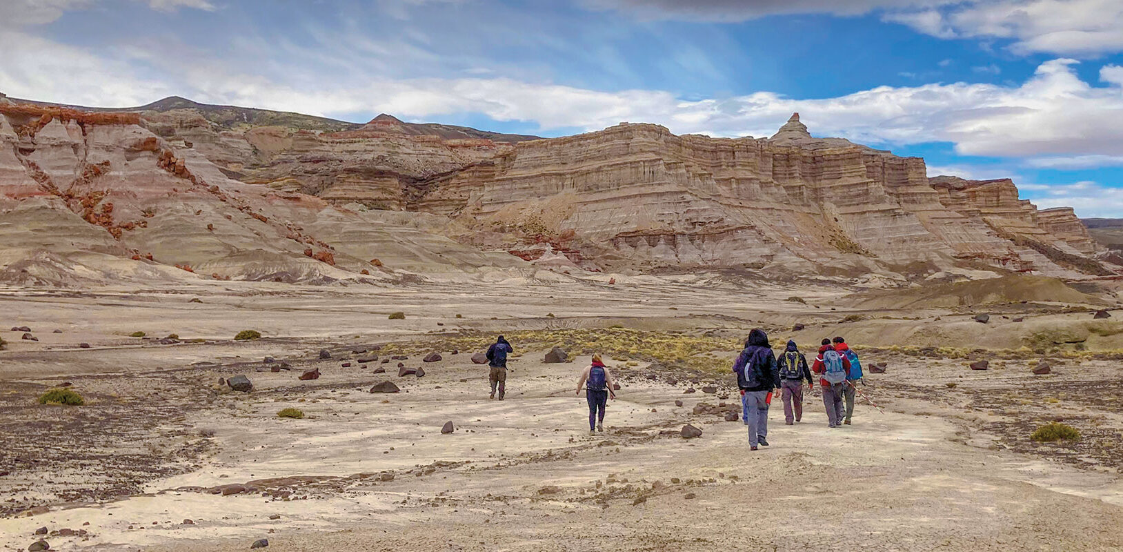 A group walking away from the camera in a large desolate area.