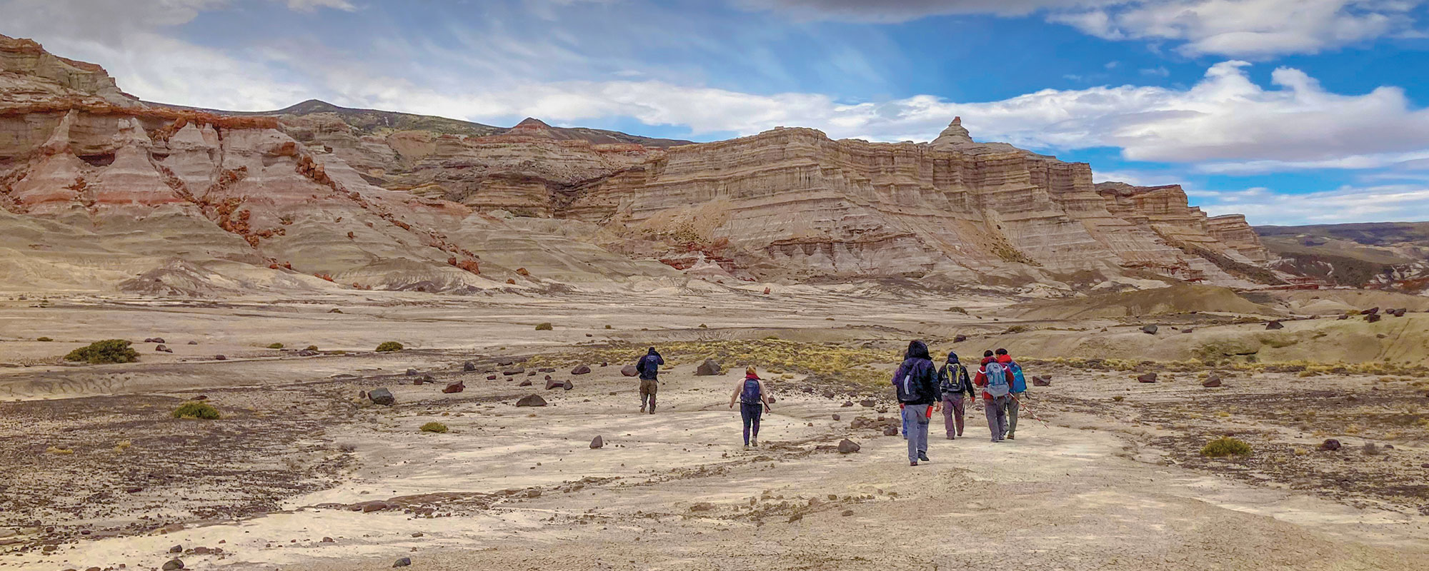 A group walking away from the camera in a large desolate area.