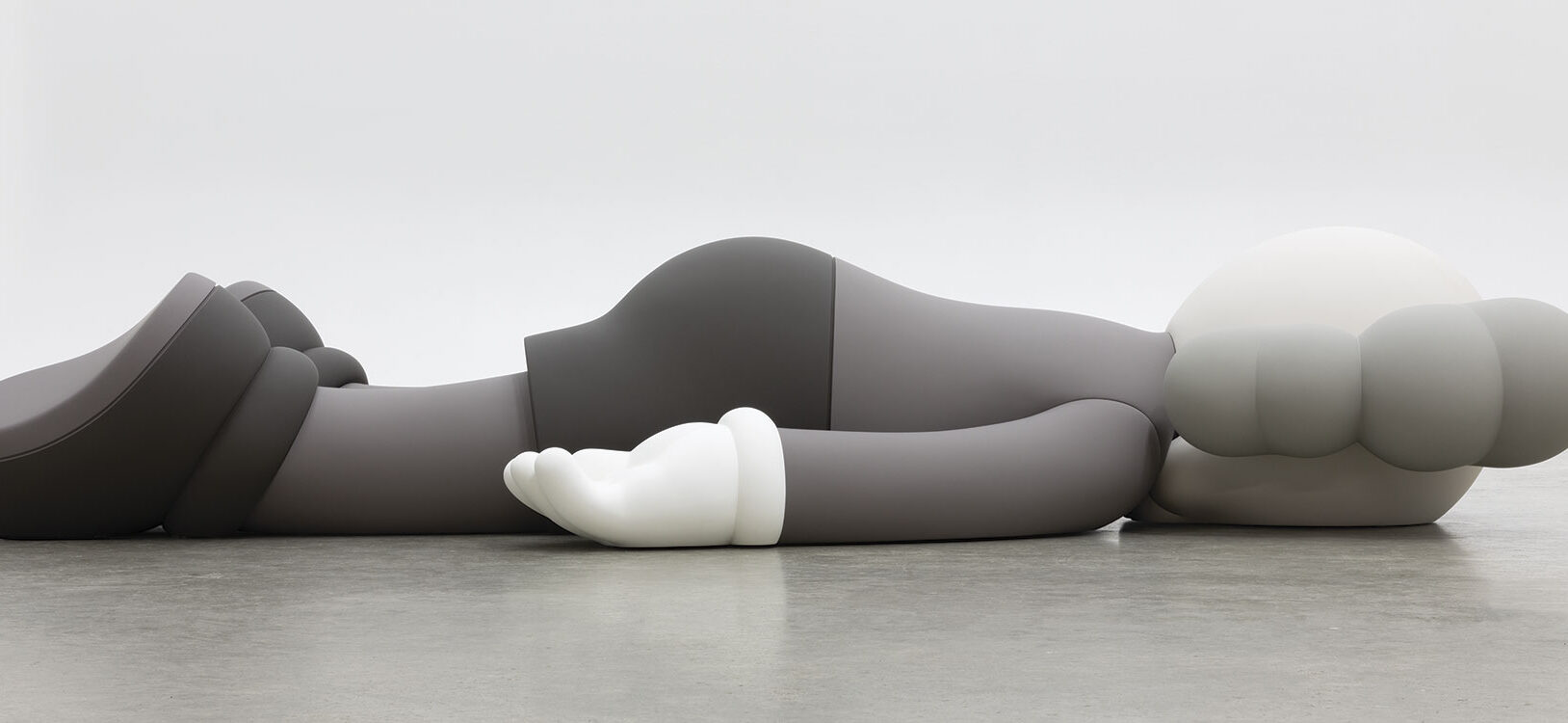 A monotone gray figure laying face down on a floor.