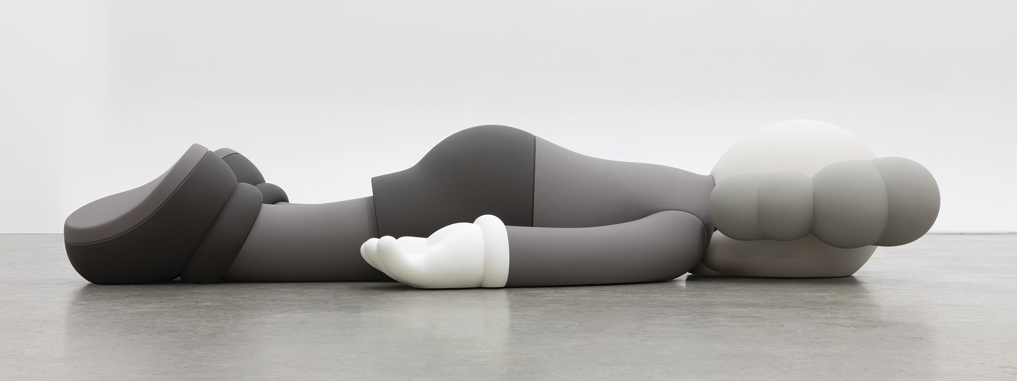 A monotone gray figure laying face down on a floor.