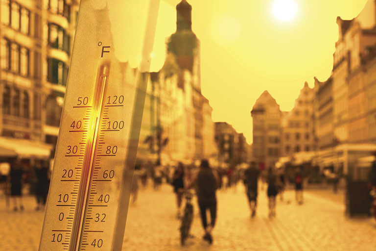 Close-up of thermometer showing high temperature on a city street
