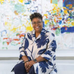 Woman sitting in front of colorful abstract art