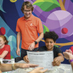 Teenagers and teacher in classroom with colorful mural