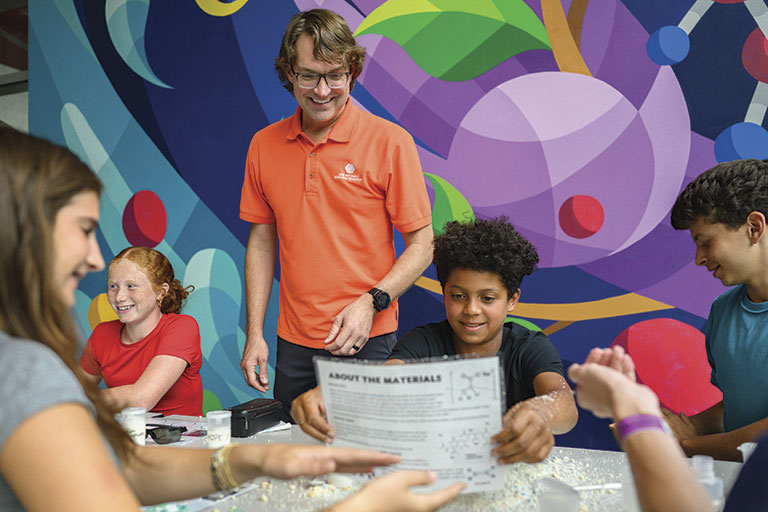 Teenagers and teacher in classroom with colorful mural