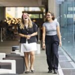 Two young women laughing together in a museum setting