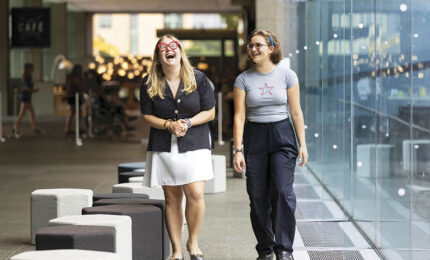 Two young women laughing together in a museum setting