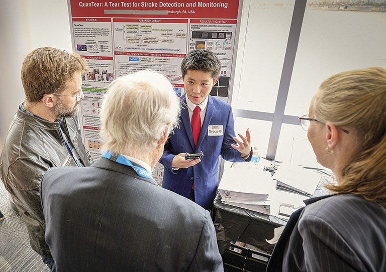 Four people discussing research on stroke detection at a science fair for teens.