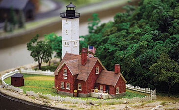Miniature model of a red house with white lighthouse